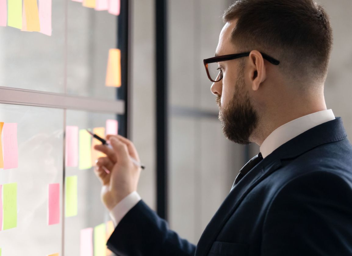 Individual in a suit writing on a post-it note