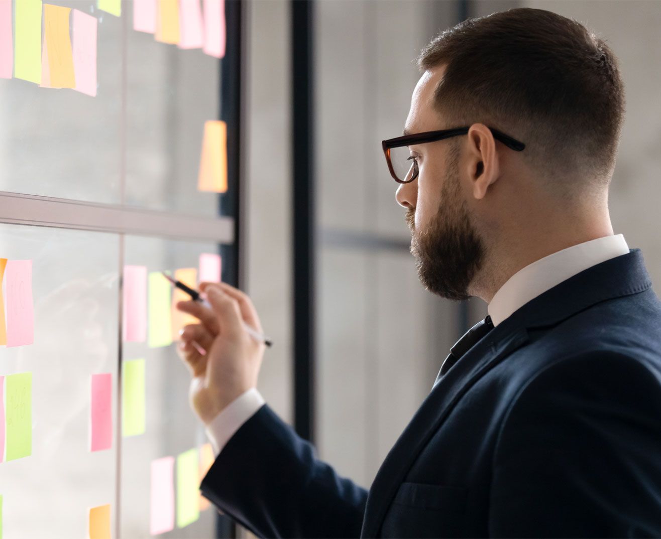 Individual in a suit writing on a post-it note