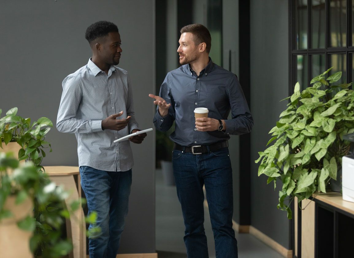 Two accountants holding a discussion, with one holding a tablet and the other holding a coffee cup