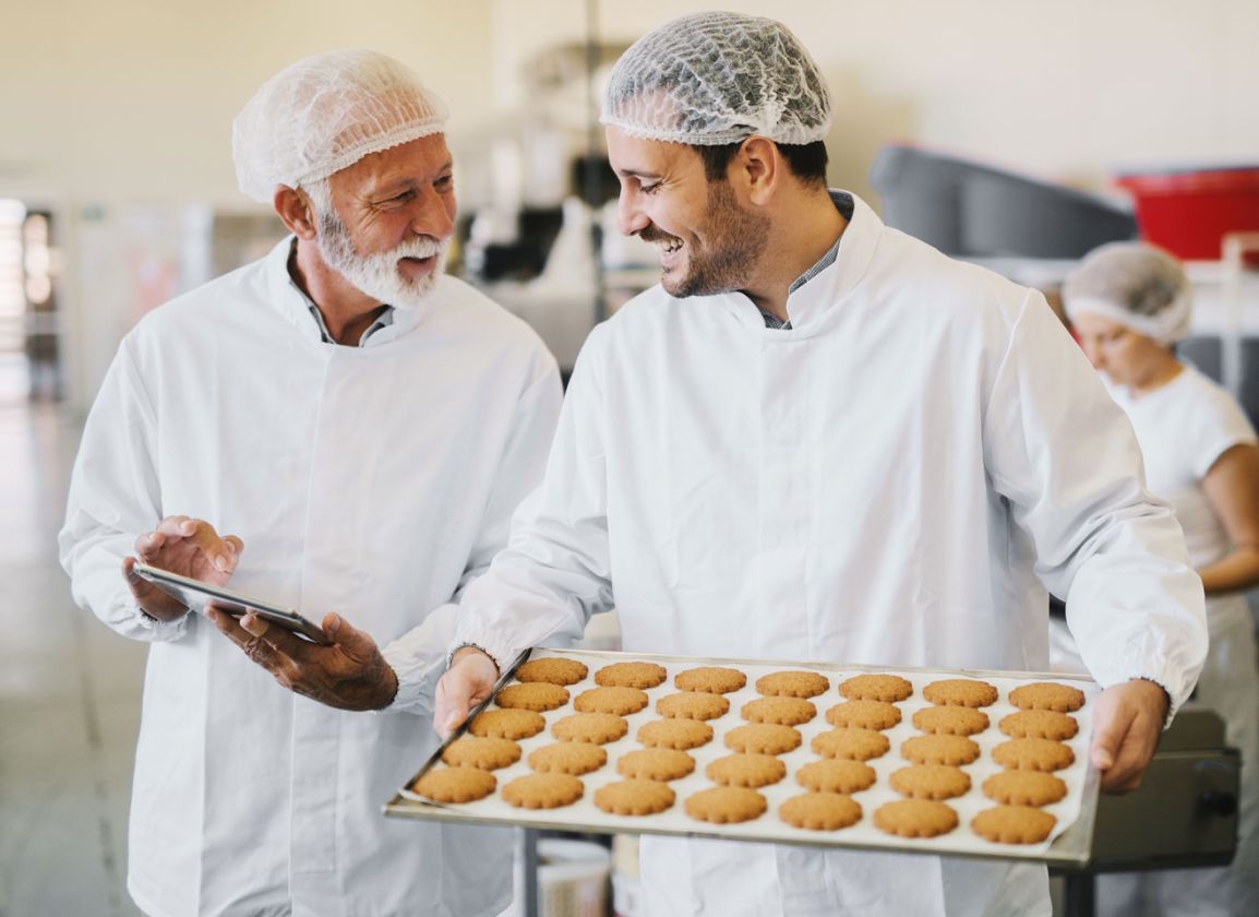 Bakers having a discussion whilst holding a tray of biscuits